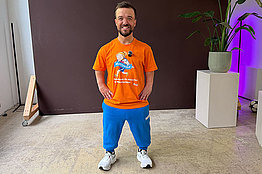 Kleinwüchsiger Mann mit orangenem MUKOmove-Shirt