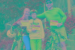 Eine Frau, ein Mann und ein Junge (vielleicht zwölf Jahre alt) stehen neben Fahrrädern im Wald und halten MUKOmove-Startnummern in der Hand. Der Junge trägt einen Fahrradhelm. 