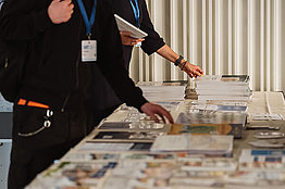 Hände greifen nach Informationsbroschüren am Infostand des Mukoviszidose e.V. 