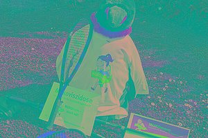 Ein Stoffpinguin trägt eine MUKOmove-T-Shirt, an ihm lehnt ein Tennisschläger. 