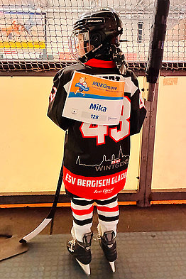 Kind mit Eishockey-Ausrüstung und MUKOmove-Startnummer - von hinten zu sehen, in einer Eishalle