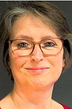 Bild Helga Rossbacher-Gnan Portrait einer Frau mit dunklen kurzen Haaren, einer Brille und einem roten Oberteil