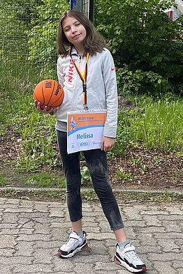 Ein Mädchen im Teenager-Alter mit Basketball und MUKOmove-Startnummer