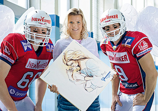 Frau steht zwischen zwei Football-Spielern mit Engelsflügeln