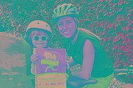 Frau und Kind mit muko.move-Plakat auf dem Fahrrad