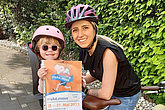 Frau und Kind mit muko.move-Plakat auf dem Fahrrad