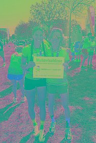 Zwei Frauen in Laufkleidung posieren mit MUKOmove-Schild. Sie waren beim Regensburger Halbmarathon für den MUKOmove dabei. 