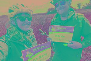 Selfie von einer Frau und einem Mann mit MUKOmove-Startnummern - sie haben Fahrradkleidung an