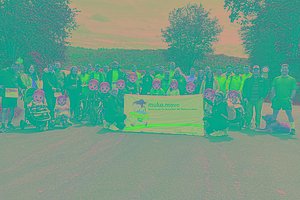 Große Gruppe von Menschen posiert auf einem Weg mit einem MUKOmove-Banner