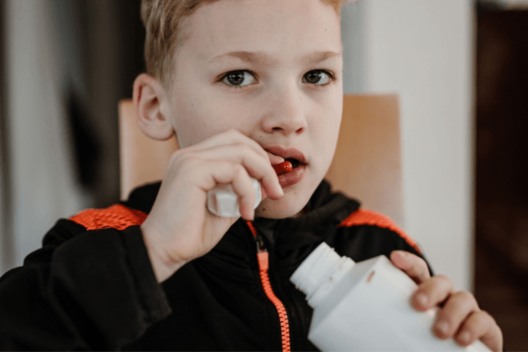 Elijah nimmt Medikamente Junge im Schulalter nimmt ein CF-Medikament ein