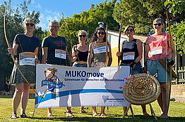 Menschen posieren mit Pfeil und Bogen und MUKOmove-Banner
