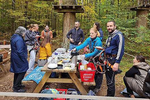 Im Kletterpark Gruppe von Menschen an einem Picknicktisch in einem Kletterpark im Herbst