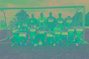 Eine Jugendfußballmannschaft posiert im Tor mit MUKOmove-Startnummern.