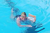 Frau schwimmt im Becken - mit muko.move-Startnummer in der Hand