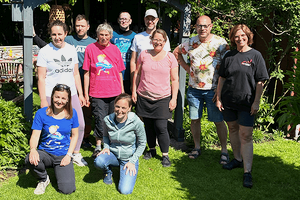 Gruppe mit MUKOmove-T-Shirts draußen im Grünen, die Sonne scheint. 