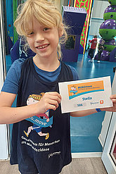 Mädchen mit MUKOmove-Shirt und MUKOmove-Startnummer in der Kletterhalle