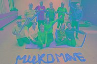 Menschen posieren in der Turnhalle mit Therabändern. Vor ihnen steht mit Theraband geschrieben: MUKOmove