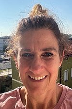 Bild Sonja Bernhart Porträt einer Frau mit zusammengebundenen braunen Haaren und einem rosa T-Shirt