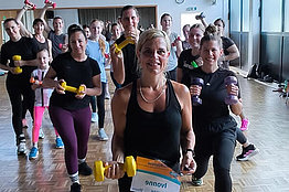 Mehrere Menschen in einem Sportraum mit Hanteln und MUKOmove-Startnummer
