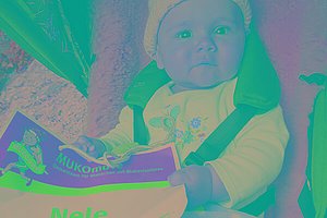 Ein Baby (Mädchen) sitzt im Kinderwagen und hält eine MUKOmove-Startnummer in der Hand, auf der man "Nele" lesen kann. 