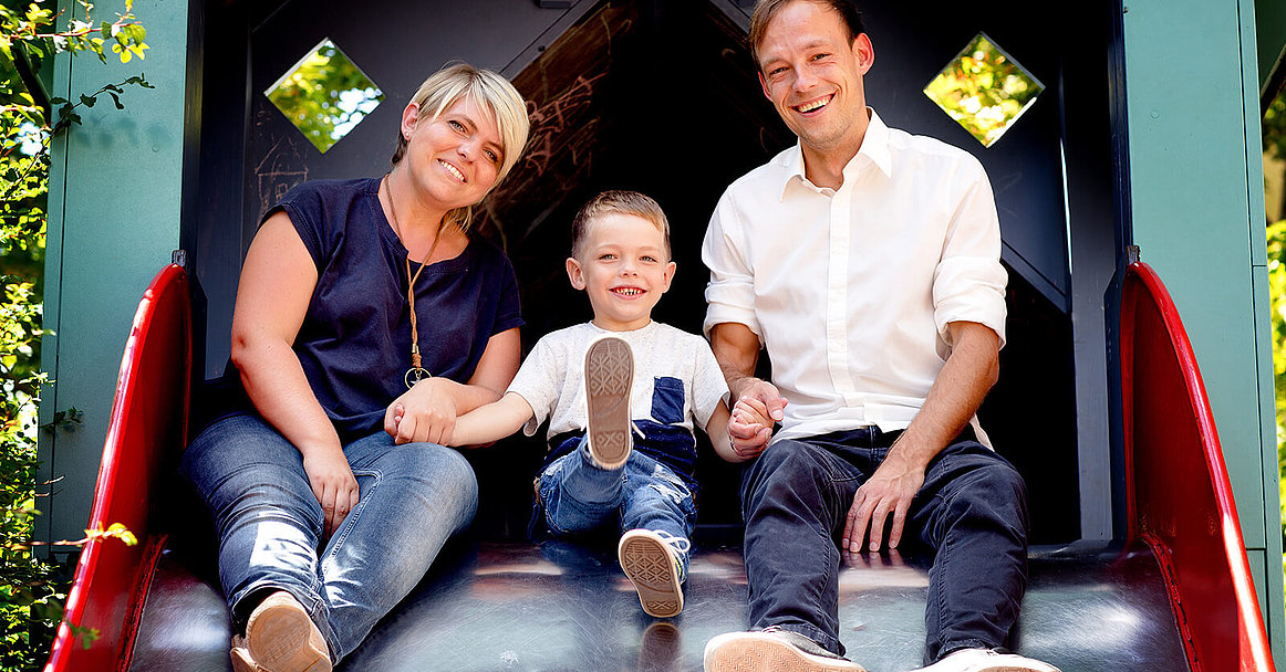 Eltern mit Kind auf der Rutsche: Der Mukoviszidose e.V. unterstützt Eltern nach der Diagnose ihres Kindes. 