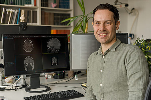 Dr. sc. hum. Niclas Hagen forscht zur KI-gestützten Auswertung von MRT-Aufnahmen Dr. sc. hum. Niclas Hagen sitzt am Schreibtisch vor seinem Computerbildschirm.