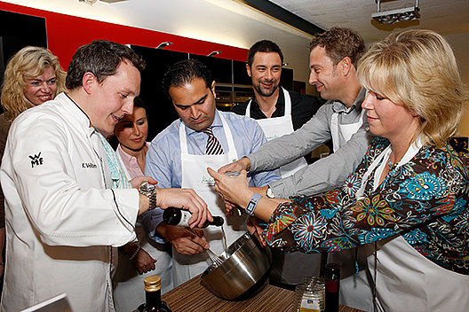 Mehrere Menschen stehen vor einer Kochschüssel und rühren