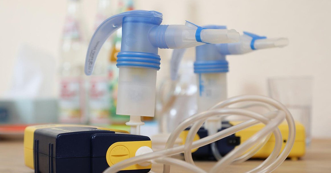 Zwei Inhalationsgeräte zur Feuchtinhalation mit Mundstück und Schlauch stehen auf einem Tisch. Foto: Floryan Neye
