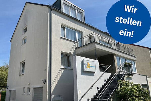 Haus Schutzengel in Hannover - weißes Haus mit mehreren Etagen. Dazu ein Button mit der Aufschrift "Wir stellen ein!"