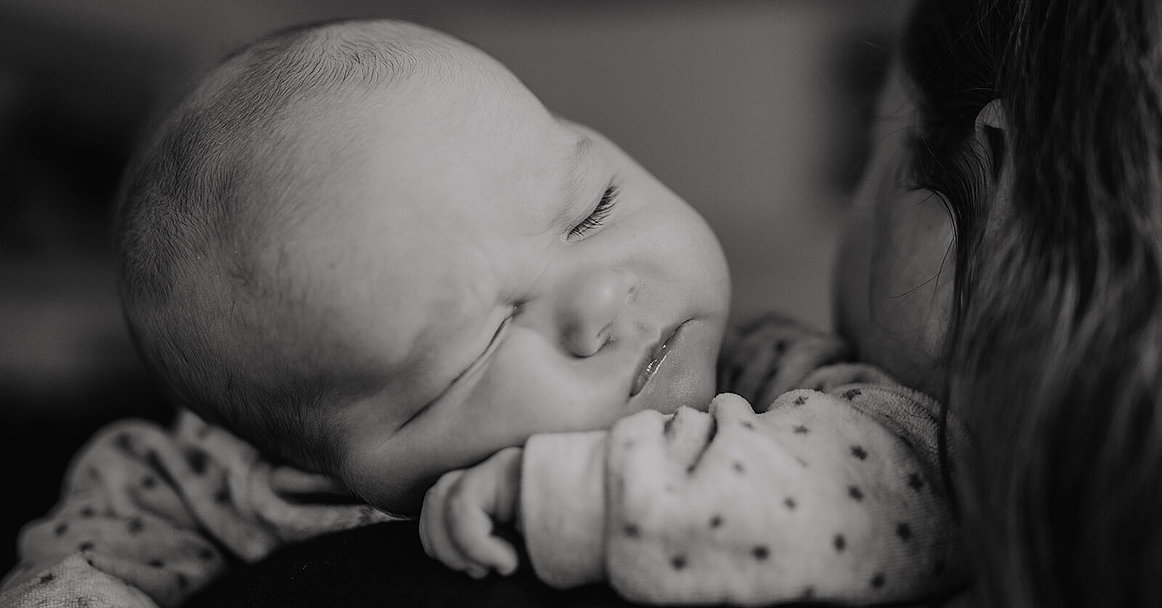 Baby ist auf der Schulter einer Person eingeschlafen. Über die Schulter fotografiert. 