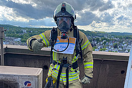 Ein Mann in Schutzkleidung wie bei der Feuerwehr hat eine Startnummer für den MUKOmove angepinnt. 