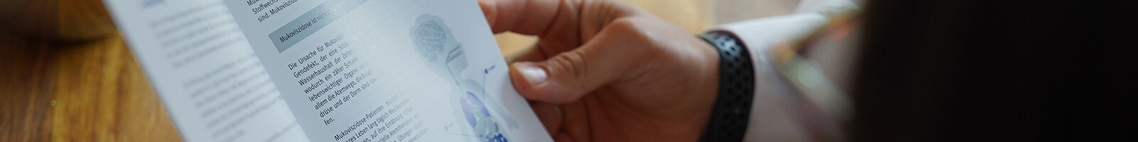 Ausschnitt einer Person, die in einer Broschüre liest