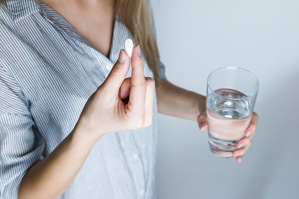 Eine Frau nimmt Tabletten ein. Quelle: Pexels