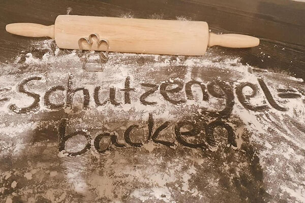 Nudelholz und Fläche mit Aufschrift: Schutzengelbacken. Mit Keksen Menschen mit Mukoviszidose helfen. 