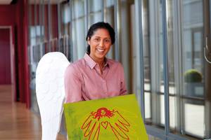 Frau trägt Schutzengelflügel und ein Bild von einem Schutzengel in der Hand